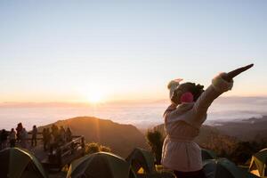 glückliche Frau wacht morgens auf dem Berg auf foto