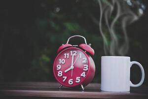 Tasse Kaffee und weiße Uhr auf Holztisch mit Bokeh foto