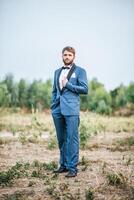 hübscher Bräutigam im Hochzeitsanzug, der im Park postet foto