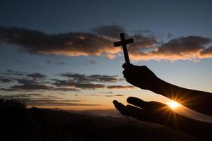 Silhouette der Hand halten das Kreuz Gottes foto