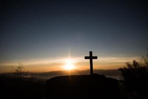 Silhouette des katholischen Kreuzes und des Sonnenaufgangs foto