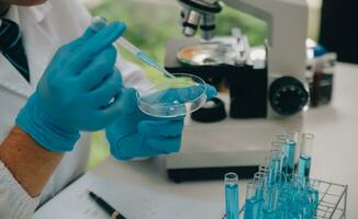 Wissenschaftler oder medizinisch im Labor Mantel Arbeiten im biotechnologische Labor, Mikroskop Ausrüstung zum Forschung mit Mischen Reagenzien im Glas Flasche im klinisch Labor. foto