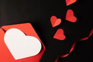 weiße Herzen und rote Herzen aus Papier werden auf schwarzem Hintergrund platziert. foto