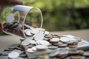 Hand, die Münzen in ein Glas mit Geldstapel setzt, wächst das Wachstum und spart Geld