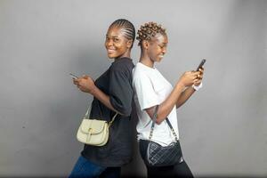 zwei jung afrikanisch Damen Gefühl aufgeregt und glücklich während Anzeigen Inhalt auf ein Telefon zusammen foto