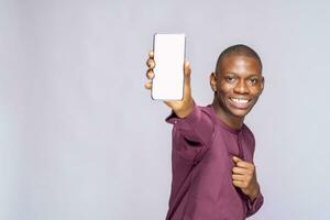 glücklich Teenager afrikanisch jung Schüler hält modern Zelle Telefon, zeigt an Handy, Mobiltelefon Telefon mit leeren Raum, zufrieden mit es ist Funktionen, Kopieren Raum zum Ihre Werbung foto