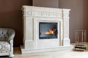 weißer Marmorkamin im klassischen Stil mit brennendem Holz im Inneren. foto