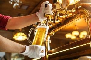 Barkeeper Hände gießen helles Bier in ein Glas foto