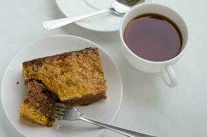 Karamell Erdnuss gekrönt Brownie Kuchen und ein Tasse von Tee foto