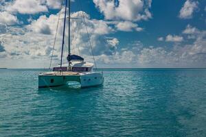 Luxusyacht in offenen Gewässern mit schönen Wolken. Katamaran weißes Segelboot in tropischer Ozeanlagune, Meereshorizont unter sonniger Skyline. idyllische Outdoor-Sport- und Reiseerholungslandschaft, Meereslandschaft foto