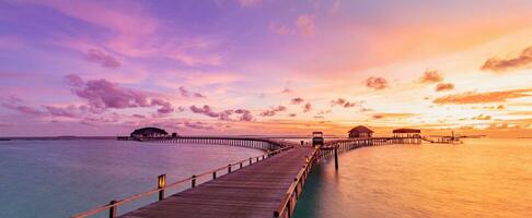tolle Strandlandschaft. schöne Aussicht auf den Sonnenuntergang auf den Malediven. horizont bunte meer himmel wolken, über wasser villa pier weg. ruhige insellagune, tourismusreisehintergrund. exotischer Urlaub foto