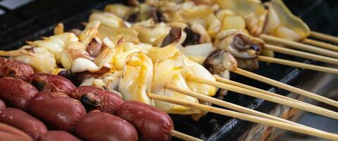 Würste und Tintenfisch sind Grillen auf das öffnen Feuer außen, Grillen Essen, Holzkohle Grillen, im Bangkok - - Thailand. foto