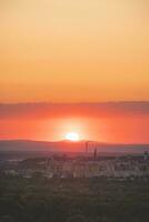 Rabatt von Sonnenuntergang mit rötlich Farbtöne setzt hinter das Berge im das Distanz. Blau, Orange und golden Himmel. Flugzeug fliegend Über im rot Sonne. abstrakt Himmel foto