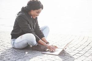 junge Frau auf der Straße, die am Laptop arbeitet foto