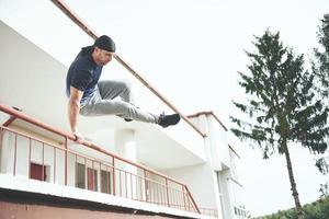 junger Mann macht Parkour-Sprung im städtischen Raum im sonnigen Frühlingssommertag der Stadt. foto