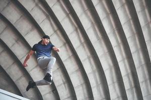 junger Mann macht Parkour-Sprung im städtischen Raum im sonnigen Frühlingssommertag der Stadt. foto