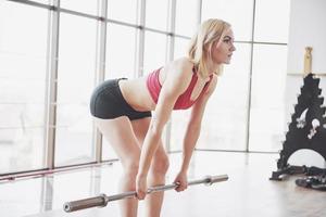 Frau, die Gewichte im Fitnessstudio-Konzept hebt, trainiert gesunden Lebensstil Sport foto