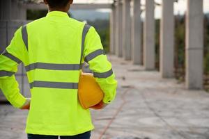 ein Arbeiter in der Uniform, der einen Helm für die Sicherheit auf der Baustelle hält foto