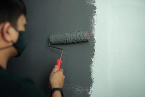 junger Mann, der eine dunkle Innenwand der Konzeptarbeit von zu Hause malt