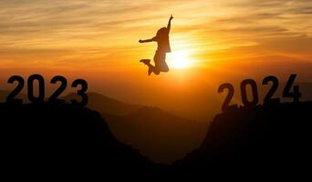 Frau springen glücklich Neu Jahr 2024 Konzept, Silhouette von Frau Springen Über Barriere Cliff und Erfolg von 2023 Cliff zu 2024 Cliff Sonnenuntergang Hintergrund. glücklich Neu Jahr zum Netz Banner und Werbung. foto