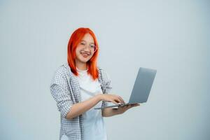 Teen Frau tragen Brille halten und Tippen Laptop isoliert auf Weiß oder grau Hintergrund, Frauen mit Laptop zu Suche oder Arbeiten oder Tippen oder Lager oder Krypto Währung. Technologie Bildung Konzept. foto