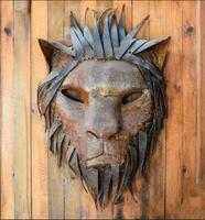 Gesicht von ein Löwe gemacht von Metall auf ein hölzern Leinwand. foto