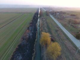 Bewässerung Kanal mit verbrannt Schilf entlang das Ufer. Asche von das Gras. foto