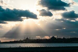 Silhouette von Istanbul mit Sonnenstrahlen zwischen das Wolken und dramatisch Himmel foto