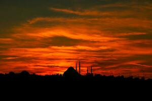 Istanbul beim Sonnenuntergang mit dramatisch Orange und rot Wolken. Silhouette von Moschee foto