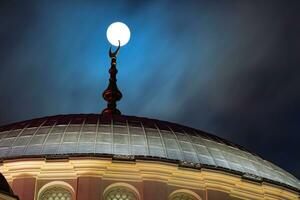 islamisch Hintergrund Foto. voll Mond berührt von das endgültig von ein Moschee Kuppel. foto