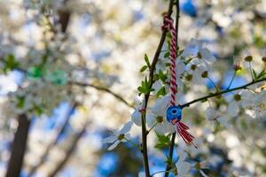 marteniza mit böse Auge Korn hängend auf das Baum Ast mit Blumen foto