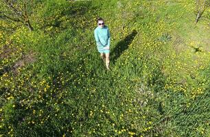 jung Mädchen im ein Licht Grün Kleid auf das Rasen mit Grün Gras. Aussicht von ein Mann von über von ein Höhe. foto