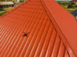 Haus mit ein Orange Dach gemacht von Metall, oben Sicht. metallisch Profil gemalt gewellt auf das Dach. foto