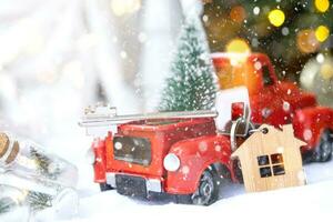 Rotes Retro-Auto mit einem Weihnachtsbaum schmückt mit dem Hausschlüssel im Pickup-Truck zu Weihnachten. Hauskauf, Umzug, Hypothek, Darlehen, Immobilien, Feststimmung, Neujahr foto