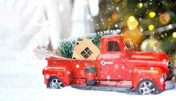 Rotes Retro-Auto mit einem Weihnachtsbaum schmückt mit dem Hausschlüssel im Pickup-Truck zu Weihnachten. Hauskauf, Umzug, Hypothek, Darlehen, Immobilien, Feststimmung, Neujahr foto