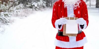 Santa claus draussen im Winter und Schnee Übergabe im Hand Öko Papier Taschen mit Kunst Geschenk, Essen Lieferung. Einkaufen, Verpackung Recycling, handgefertigt, Lieferung zum Weihnachten und Neu Jahr foto