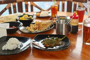 Sundanesisch Restaurant Speisekarte, Westen Java, Indonesien. sauer Gemüse, gebraten Gurami, Grünkohl und Reis. auf hölzern Tisch. foto