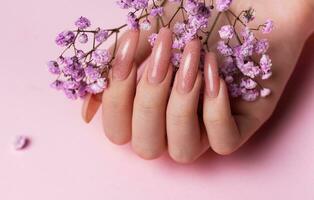 weiblich Hände mit Rosa Nagel Design halt Gypsophila Blumen. foto