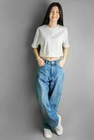 voll Länge Porträt von ein jung Mädchen im ein Weiß T-Shirt und Jeans. foto