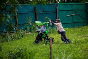 zwei Kinder spielen im das Hof mit ein Grün Regenschirm foto
