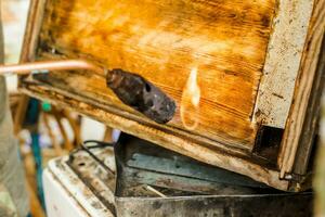 wird bearbeitet von Biene Frames und Nesselsucht zum das Honig Ernte Jahreszeit. Brennen das hölzern Teile von das Bienenstock mit ein Lötlampe. Bienenzucht Arbeit im das Frühling und nach Winter. foto