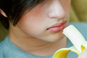 Porträt von ein Teenager Junge Essen ein Banane. Foto von ein Leute Mund und Lippen mit ein Banane. frisch Frucht. gesund Lebensmittel zum Kinder
