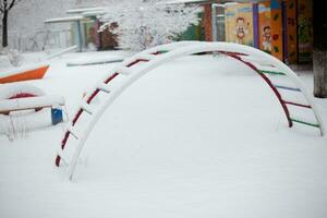 Kinder- Spielplatz im das Park während ein Schneefall im Winter. foto