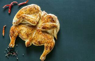 Gegrilltes Huhn mit Zutaten auf dem dunklen hölzernen Hintergrund foto