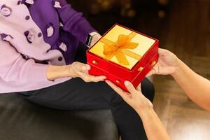 Tochter geben Geschenk Box zu Mutter beim heim. foto