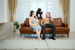 ein glücklich Familie sitzt auf das Sofa im das Leben Zimmer, Vater und Tochter sind schwanger Trinken Milch und sich unterhalten zu jeder andere. foto