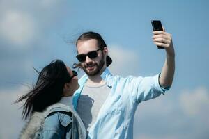 glücklich jung Paar nehmen Selfie mit Smartphone im Vorderseite von Windmühlen foto