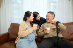 ein glücklich Familie sitzt auf das Sofa im das Leben Zimmer, Vater und Tochter sind schwanger Trinken Milch und sich unterhalten zu jeder andere. foto