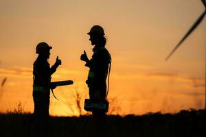 Silhouette von Ingenieur im aufladen von Wind Energie gegen ein Hintergrund von Wind Turbinen. foto