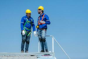 beide von Techniker reparieren Solar- Paneele sich ausruhen im das sengend Sonne auf ein Fabrik Dach bedeckt mit Solar- Paneele zu erhalten Solar- Energie. foto